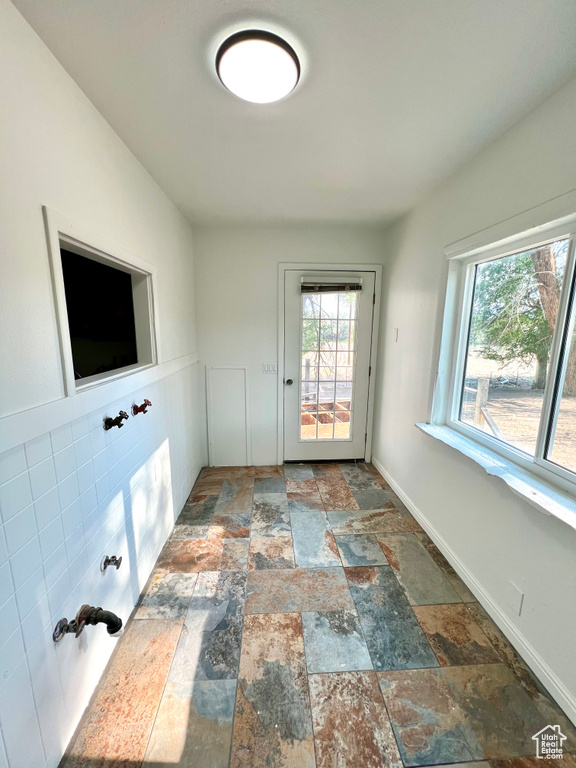 Unfurnished room featuring stone tile flooring and healthy amount of natural light