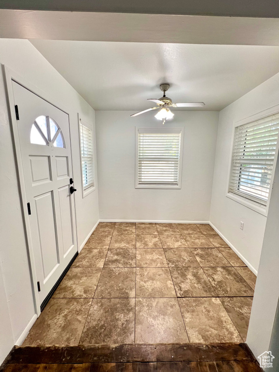 Foyer entrance with ceiling fan and baseboards