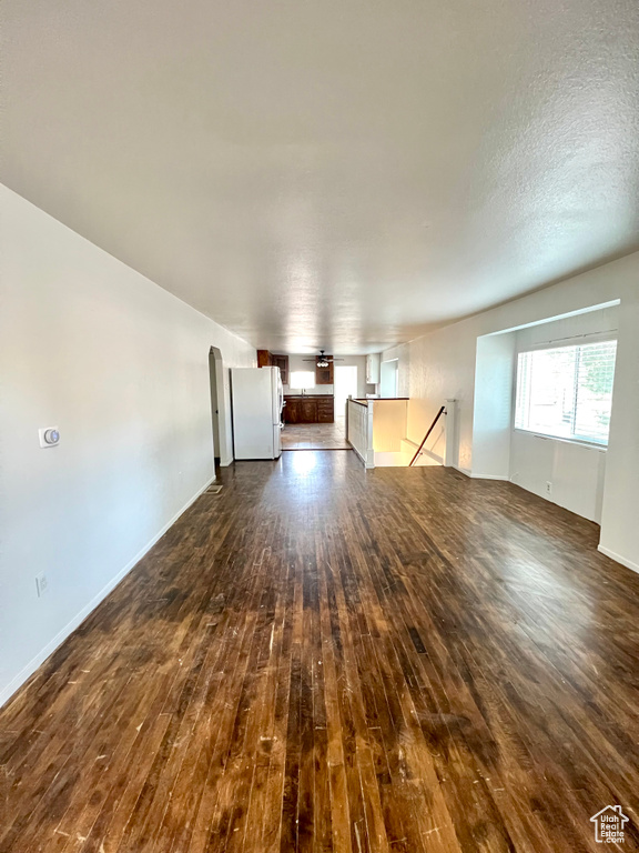 Unfurnished living room with dark wood finished floors and healthy amount of natural light