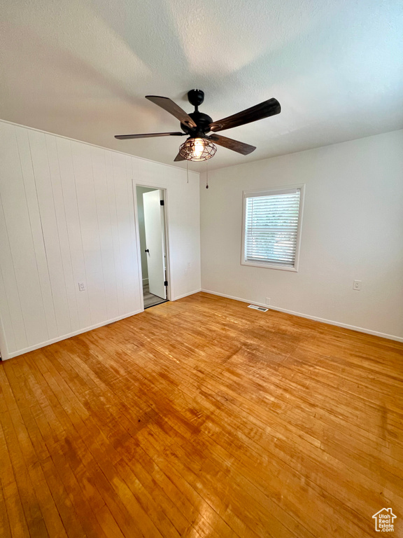 Spare room with light wood finished floors, ceiling fan, and a textured ceiling