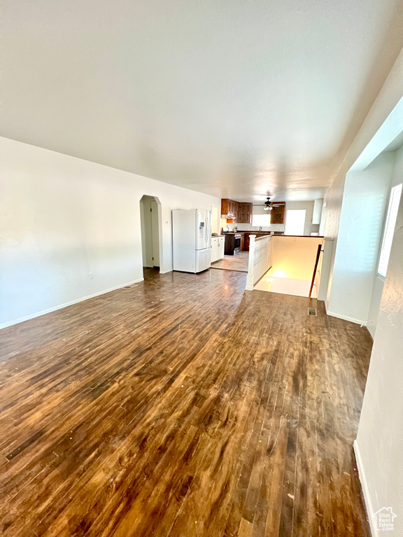Unfurnished living room with dark wood-style flooring and arched walkways