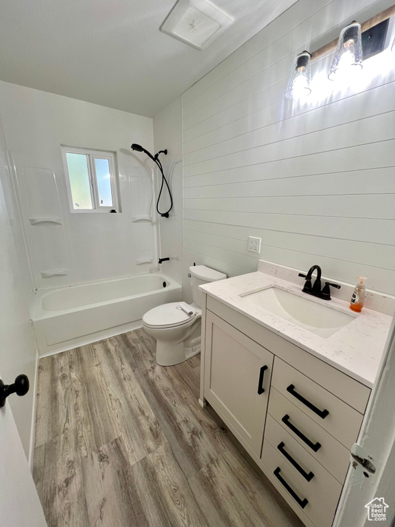 Bathroom featuring vanity, wood finished floors,  shower combination, and wooden walls