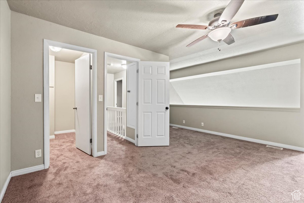 Unfurnished bedroom with carpet floors, lofted ceiling, a textured ceiling, and a ceiling fan
