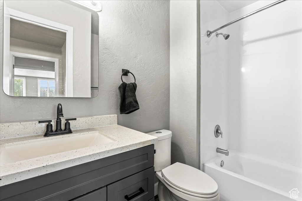 Full bathroom with vanity, bathing tub / shower combination, and a textured wall