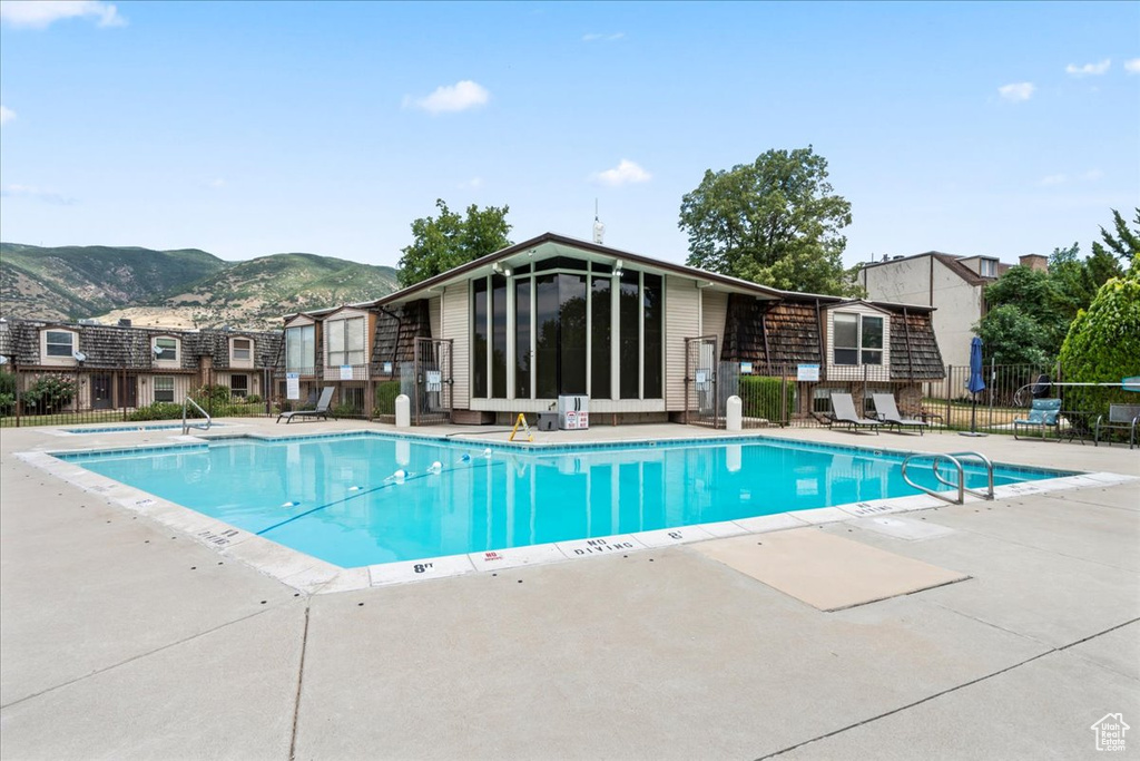 Community pool featuring a mountain view, a patio, and a sunroom