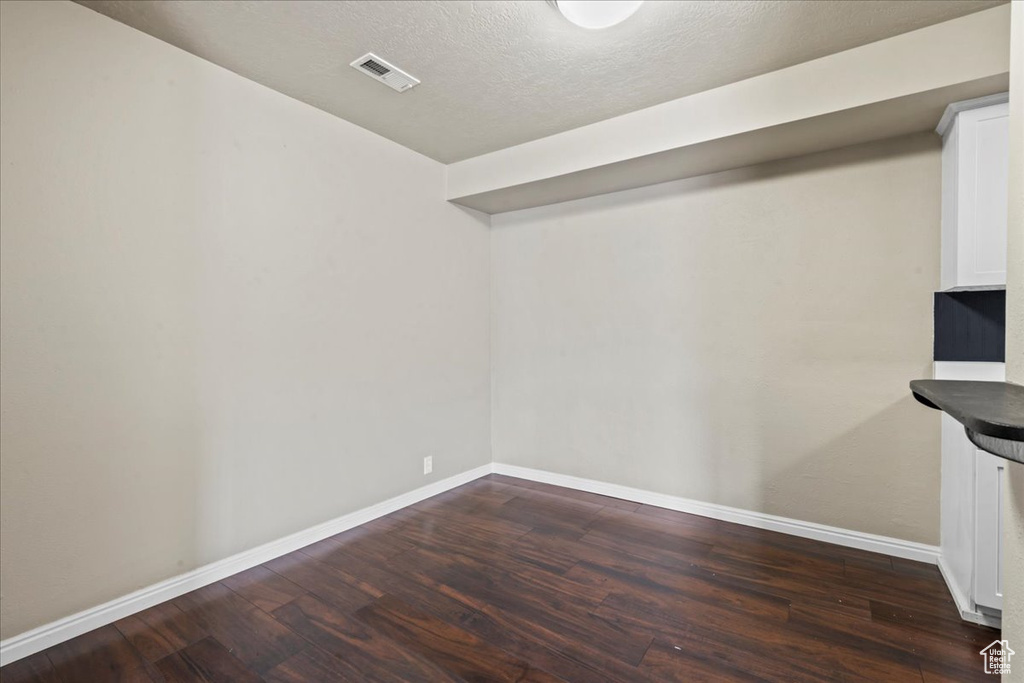 Basement featuring dark wood-type flooring and a textured ceiling