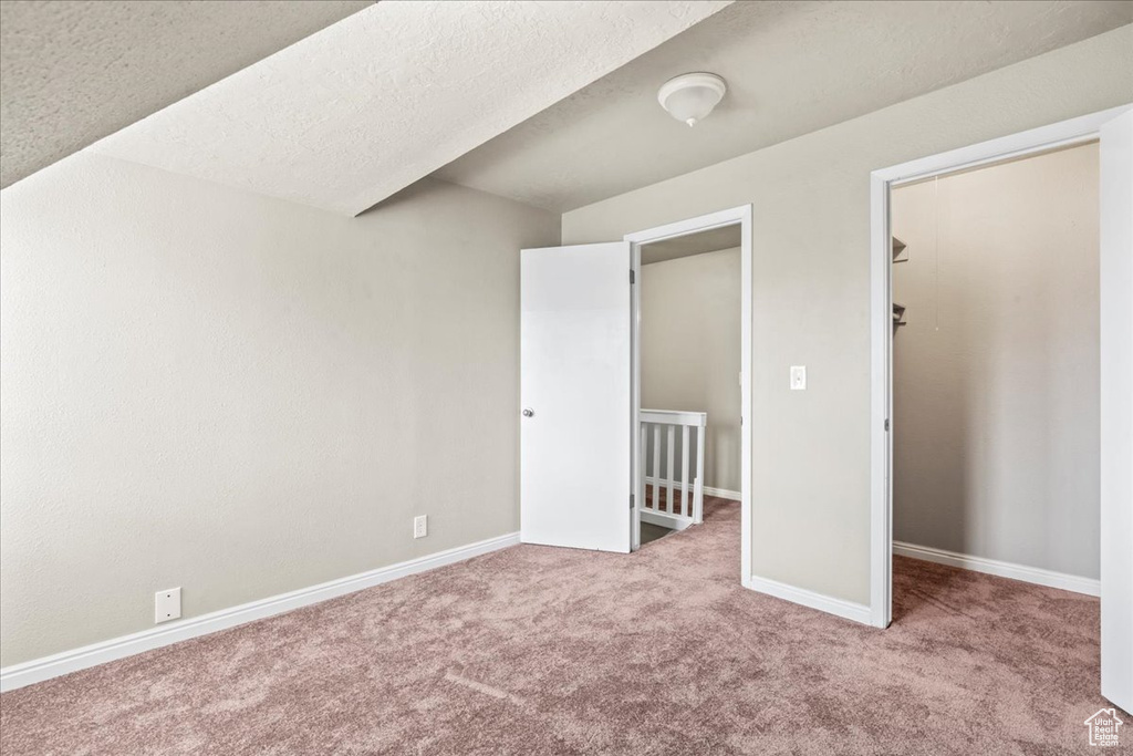 Unfurnished bedroom featuring carpet flooring, a spacious closet, a closet, and a textured ceiling