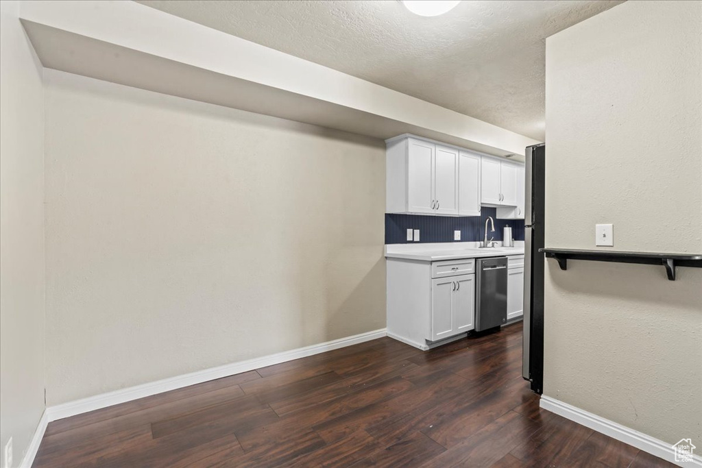 Kitchen featuring dishwasher, dark wood finished floors, white cabinetry, light countertops, and a textured ceiling