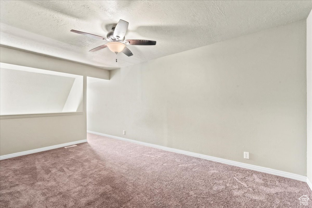 Carpeted spare room with ceiling fan and a textured ceiling