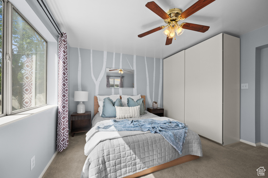 Carpeted bedroom with a ceiling fan and a closet
