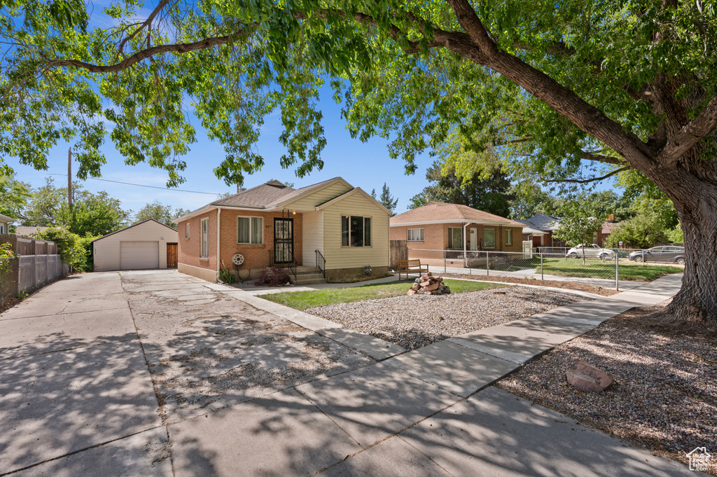 View of front of house with a garage, an outdoor structure, concrete driveway, and brick siding