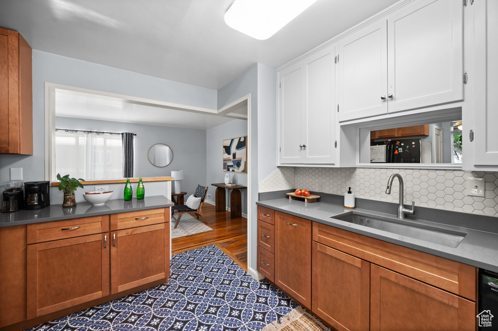 Kitchen featuring decorative backsplash, white cabinets, dark countertops, and wood finished floors