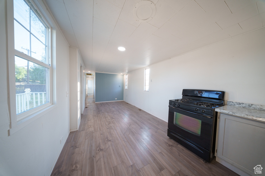 Kitchen featuring black gas range, dark wood-style floors, and healthy amount of natural light