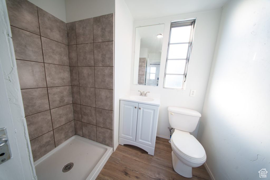 Full bath with vanity, wood finished floors, and a tile shower