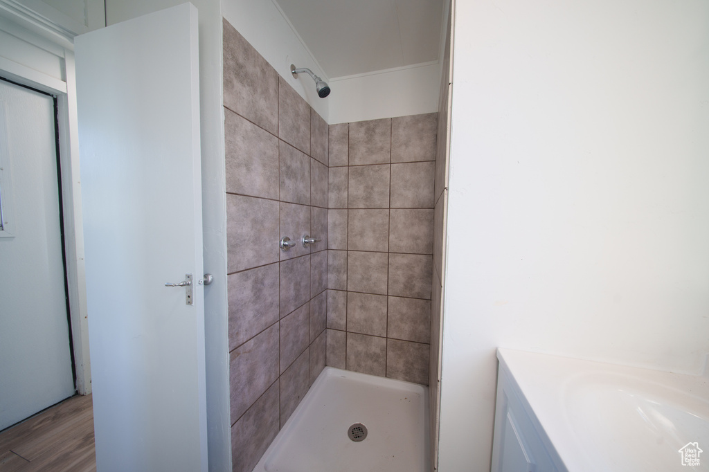 Bathroom with tiled shower, wood finished floors, and vanity
