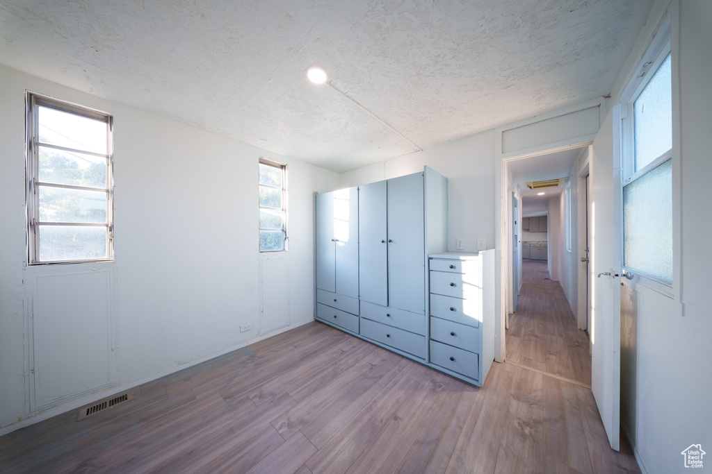 Unfurnished bedroom with wood finished floors, a textured ceiling, and a closet