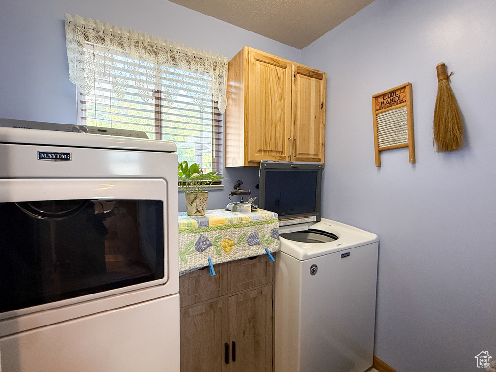 Washroom featuring washer / dryer and cabinet space