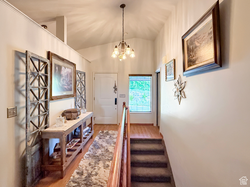 Foyer entrance featuring wood finished floors, lofted ceiling, and a chandelier