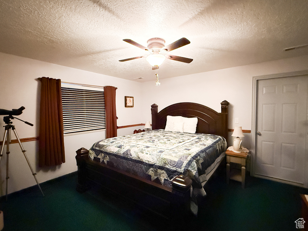Carpeted bedroom featuring a textured ceiling and ceiling fan