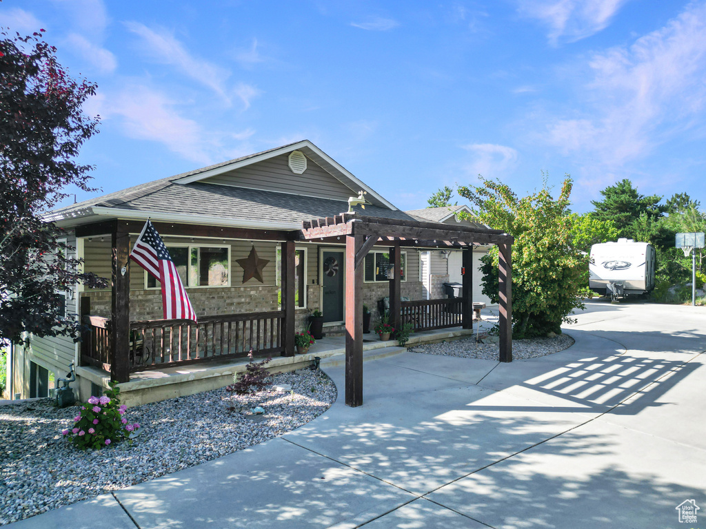 View of front of property featuring a porch, a pergola, and roof with shingles