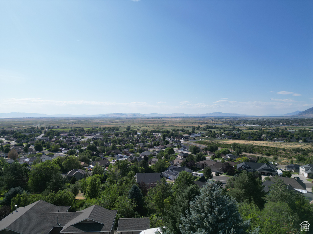 Aerial view of property and surrounding area featuring a mountainous background and nearby suburban area