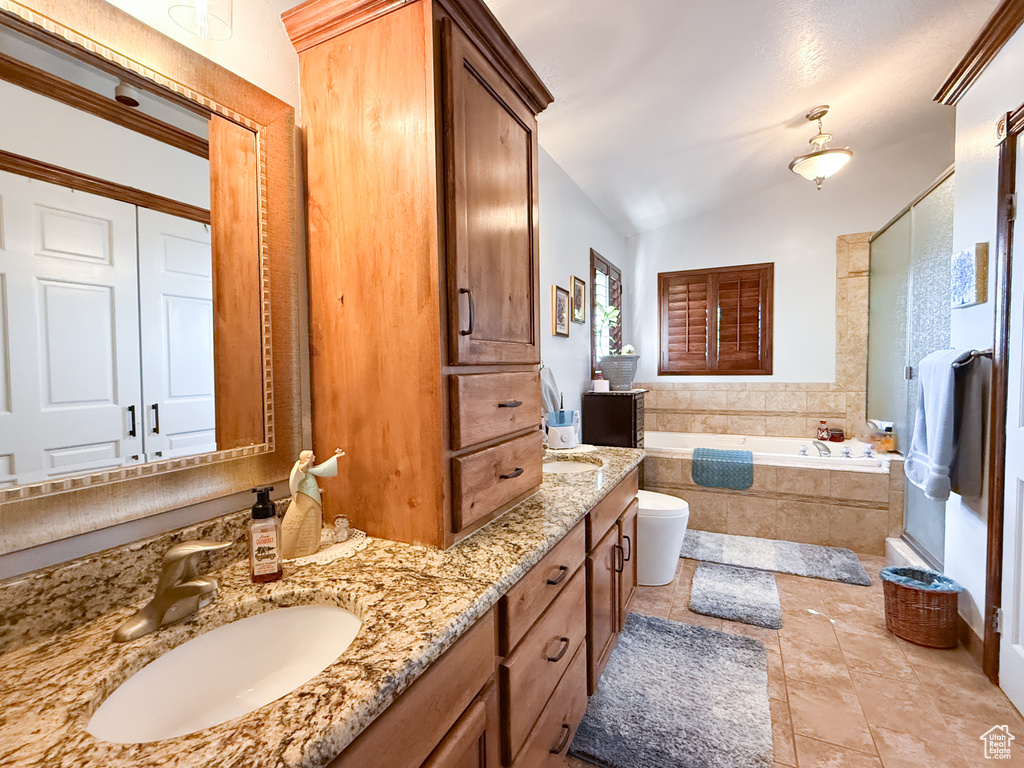 Bathroom featuring a garden tub, double vanity, vaulted ceiling, and tile patterned floors