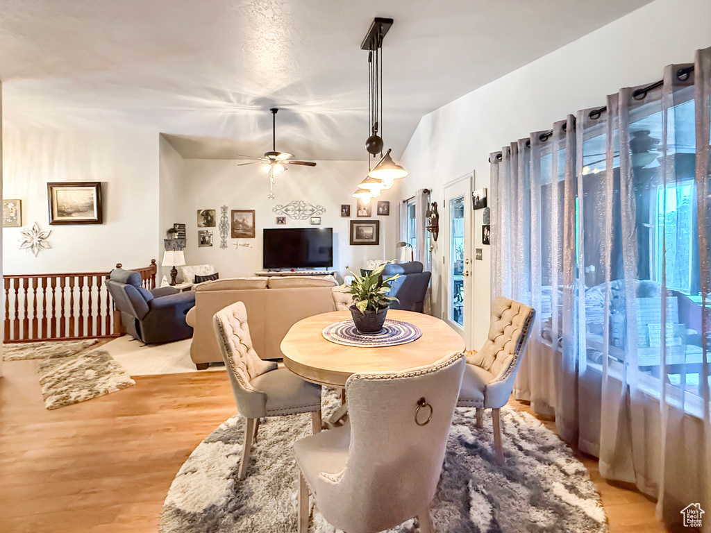 Dining space featuring a ceiling fan, light wood-type flooring, and vaulted ceiling