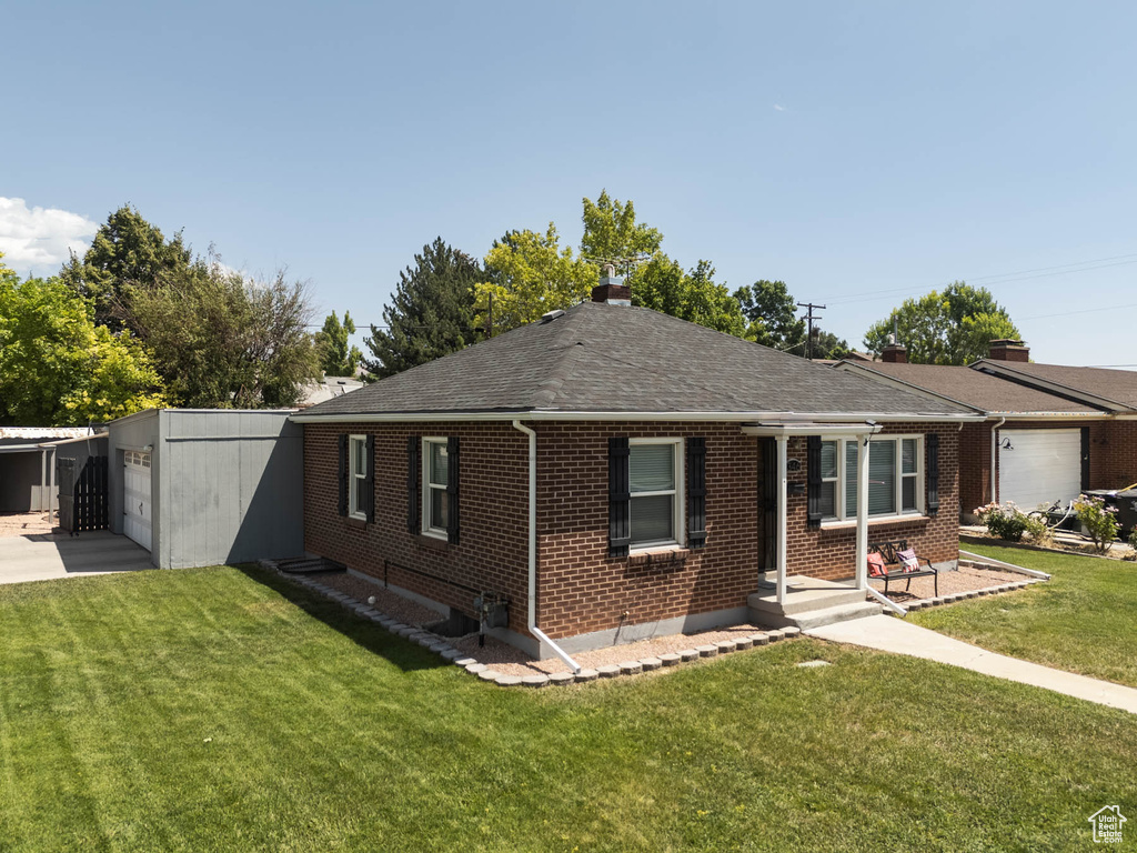 View of front of property featuring brick siding, a front lawn, a shingled roof, driveway, and a garage