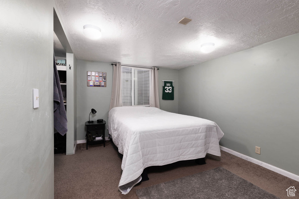 Carpeted bedroom with a textured ceiling and baseboards