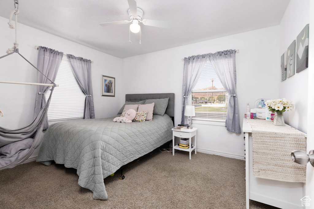 Carpeted bedroom featuring ceiling fan and baseboards