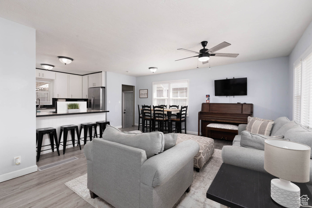 Living room with ceiling fan and light wood-style floors