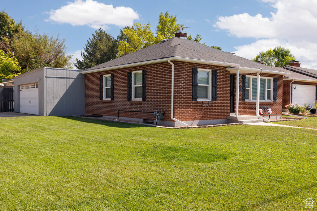 Ranch-style house featuring brick siding, a chimney, a front lawn, an attached garage, and roof with shingles