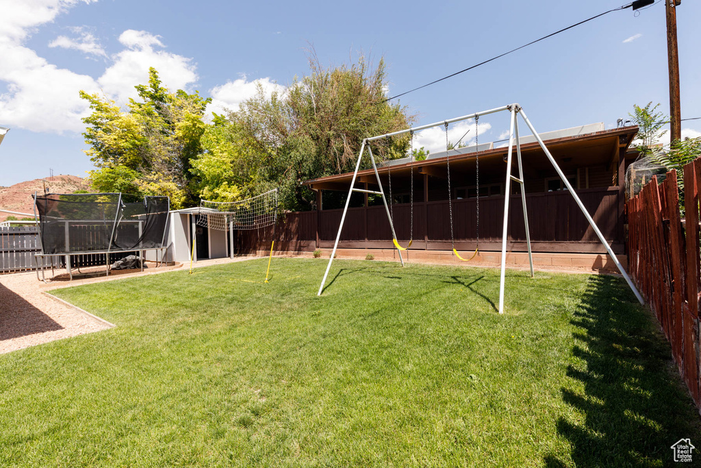 Fenced backyard featuring a trampoline