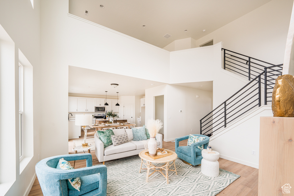 Living area featuring a high ceiling, light wood finished floors, and stairway