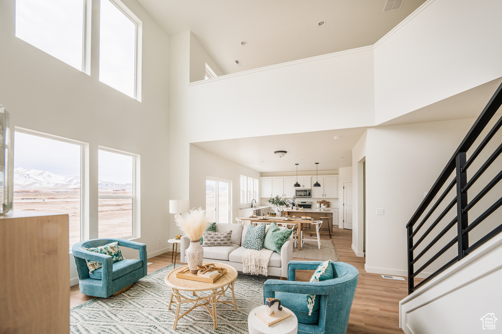 Living area featuring stairs, light wood-type flooring, and a towering ceiling