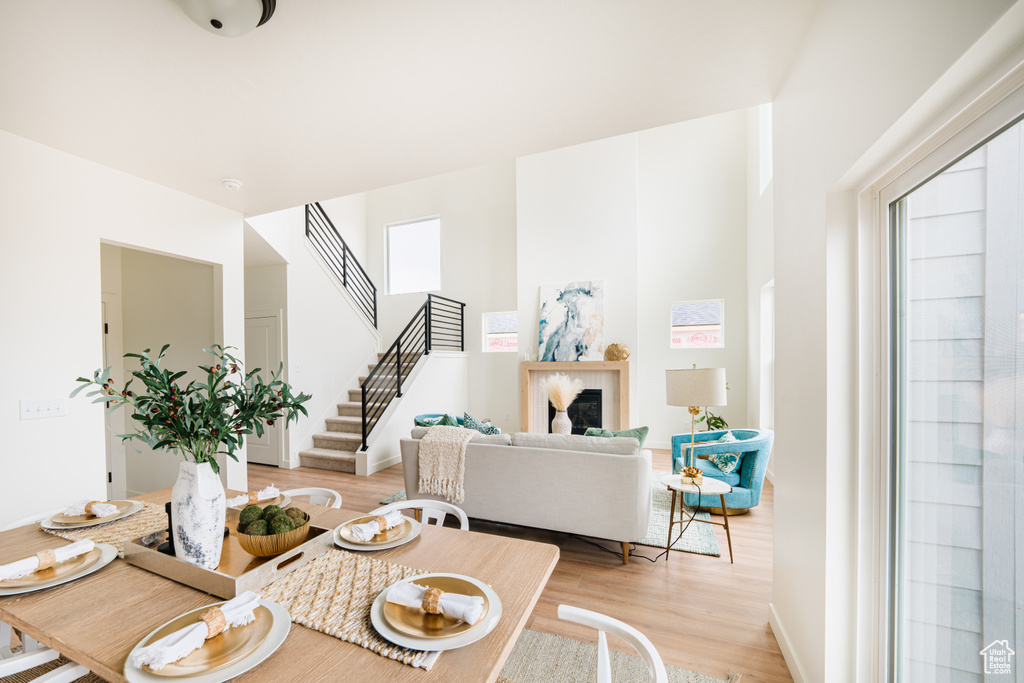 Dining space with light wood-style flooring, stairs, and a fireplace