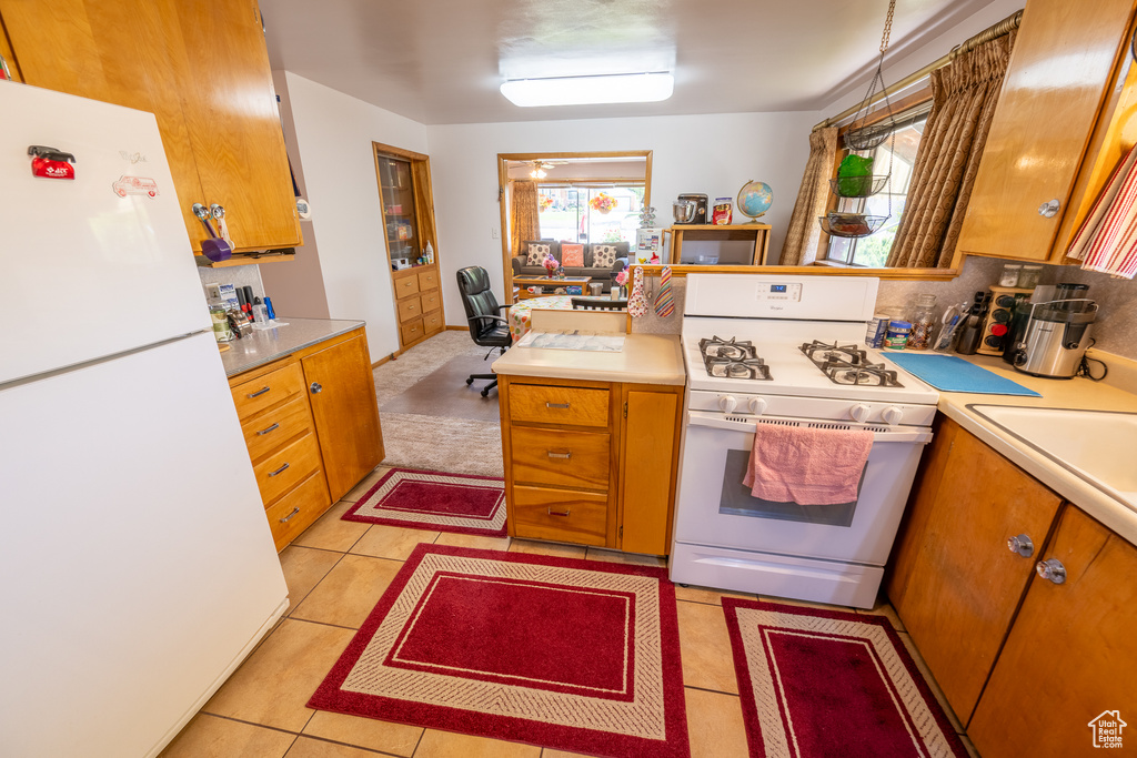 Kitchen featuring white appliances, light countertops, and brown cabinetry