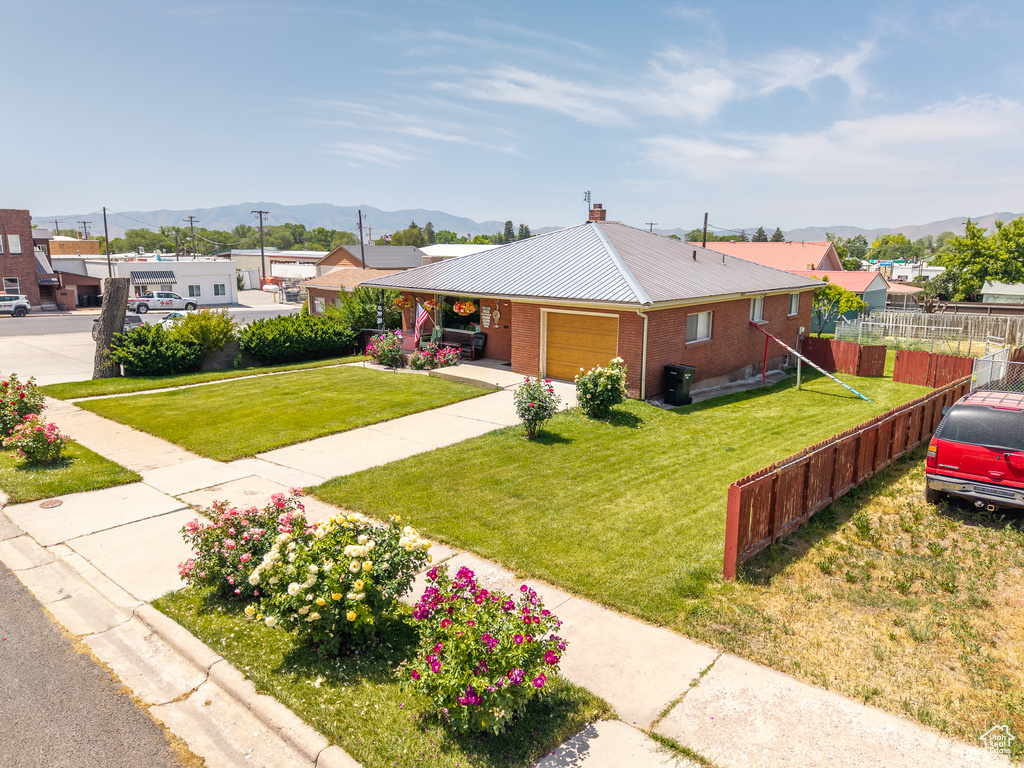 Single story home featuring a mountain view, a garage, a metal roof, brick siding, and a chimney