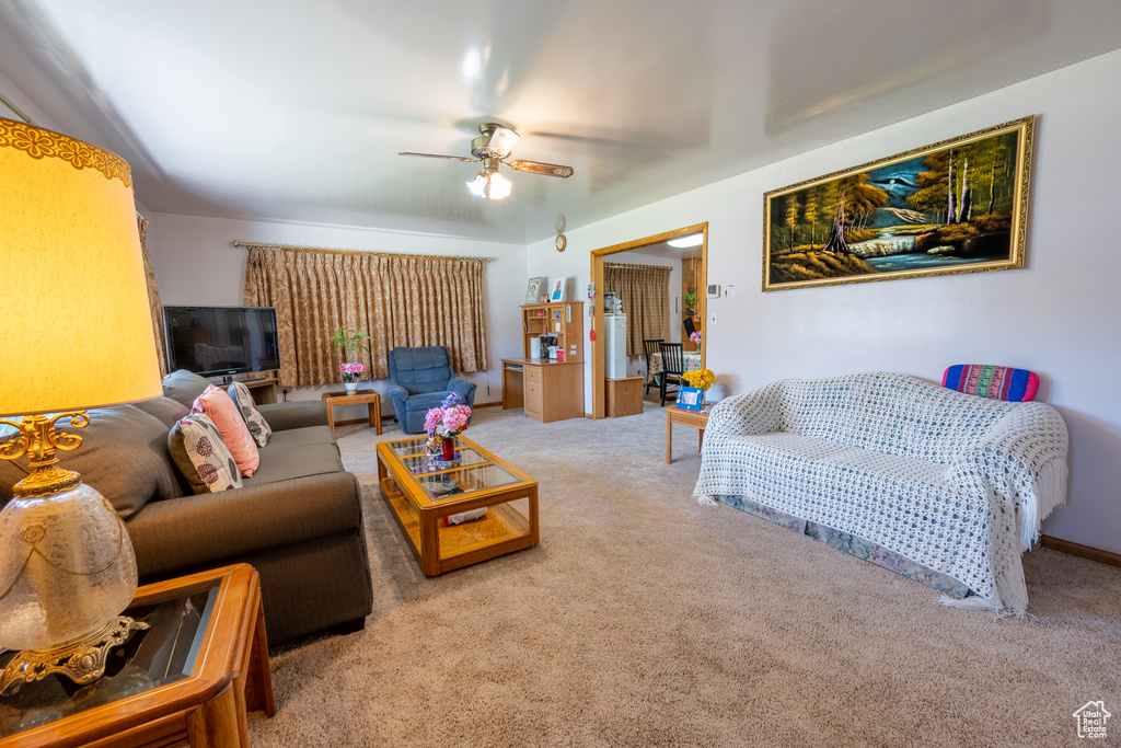 Carpeted living area featuring a ceiling fan