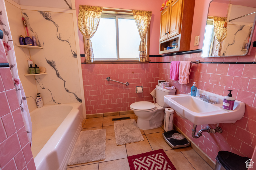 Bathroom featuring tile patterned flooring, tile walls, shower / bath combo, and a wainscoted wall