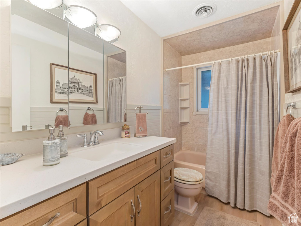 Bathroom featuring vanity, wood finished floors, and shower / bathtub combination with curtain
