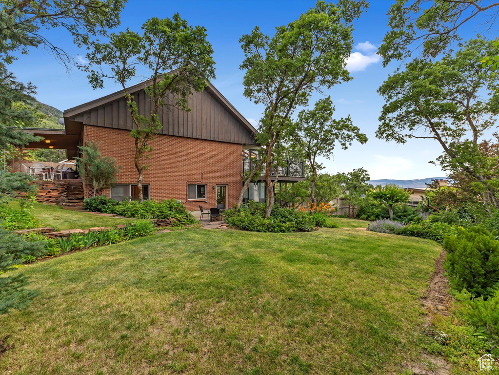 View of home\\\\\\\'s exterior with brick siding, board and batten siding, a lawn, and a patio