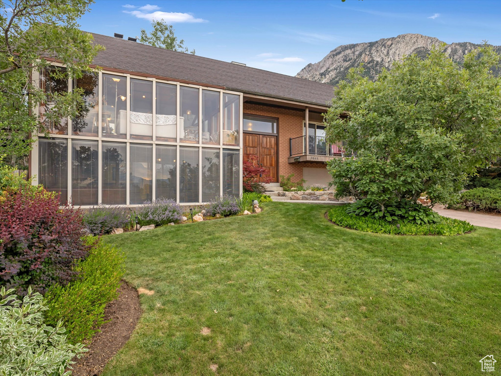 Back of house with a yard, a mountain view, and brick siding