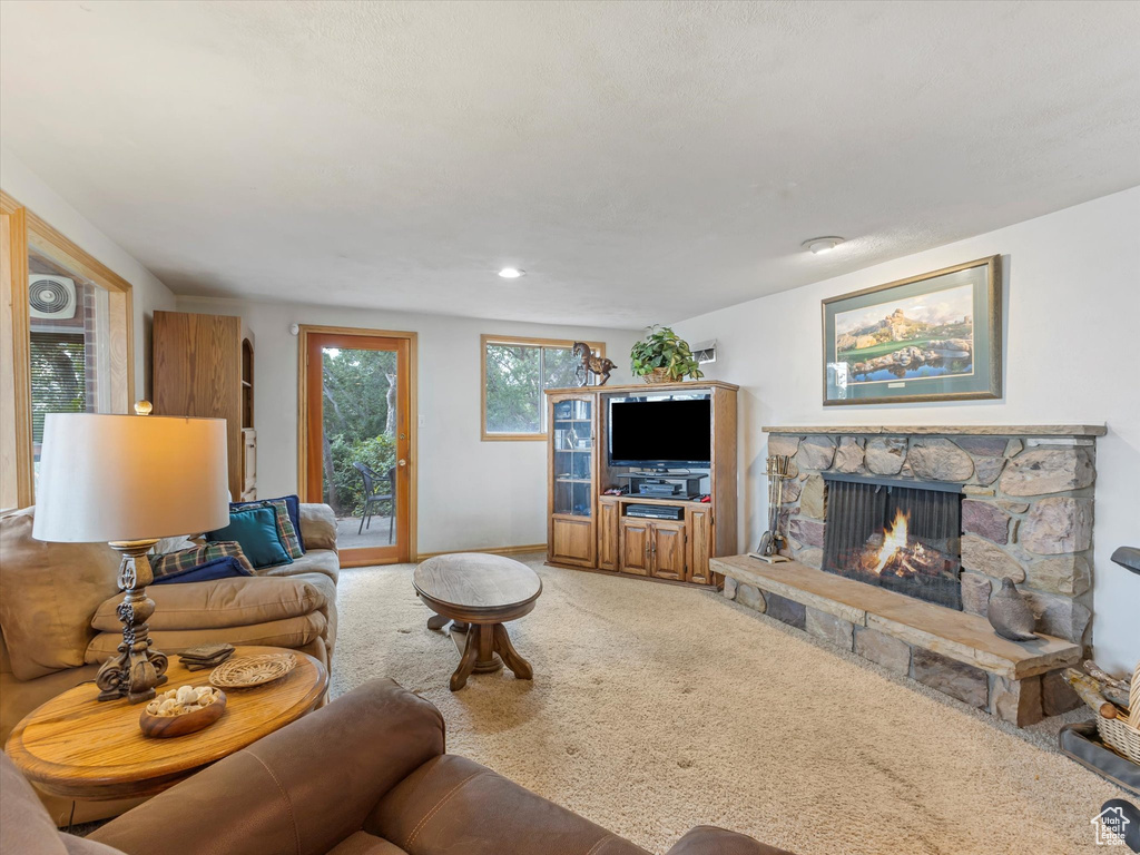 Living area with a stone fireplace and light colored carpet
