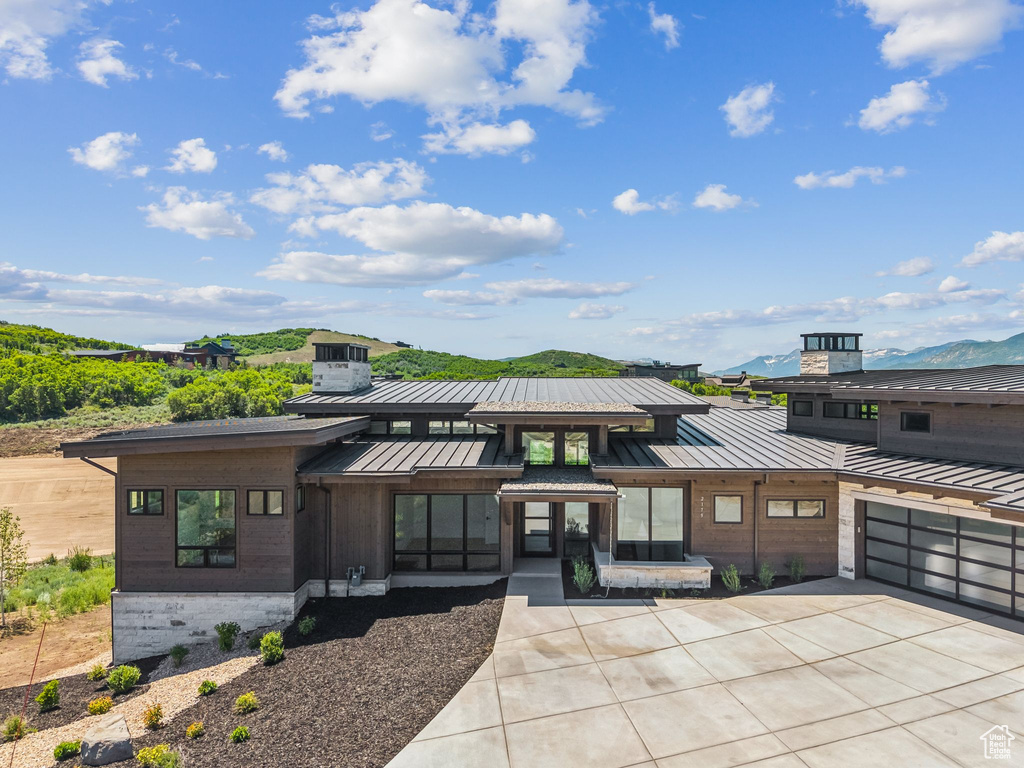 View of front of home featuring a standing seam roof, a metal roof, driveway, and a mountain view