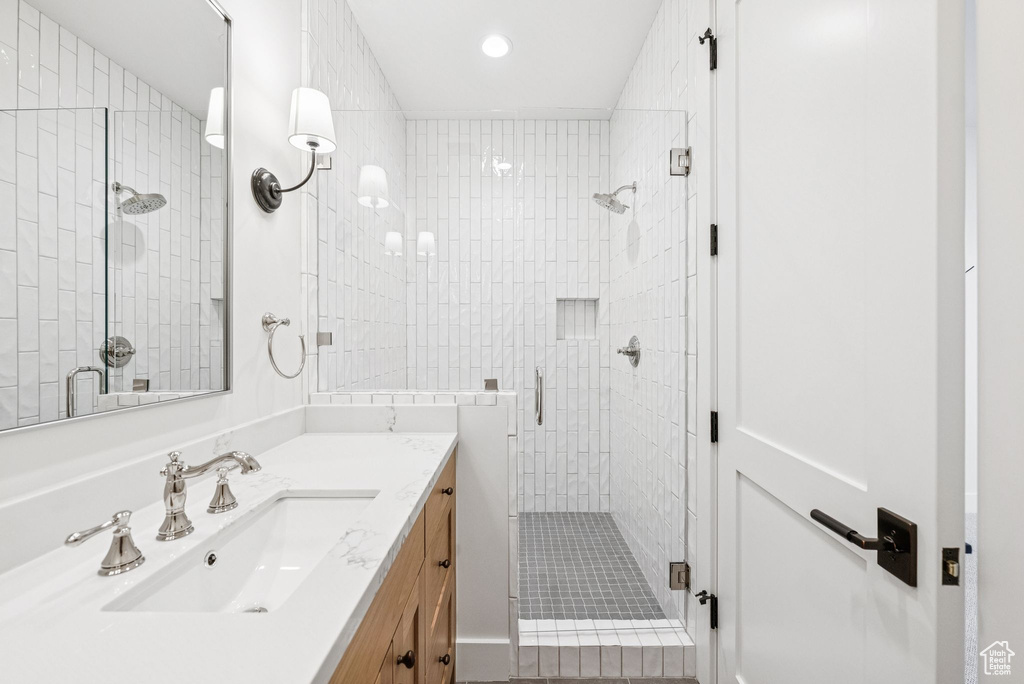 Bathroom with a shower stall, vanity, and recessed lighting