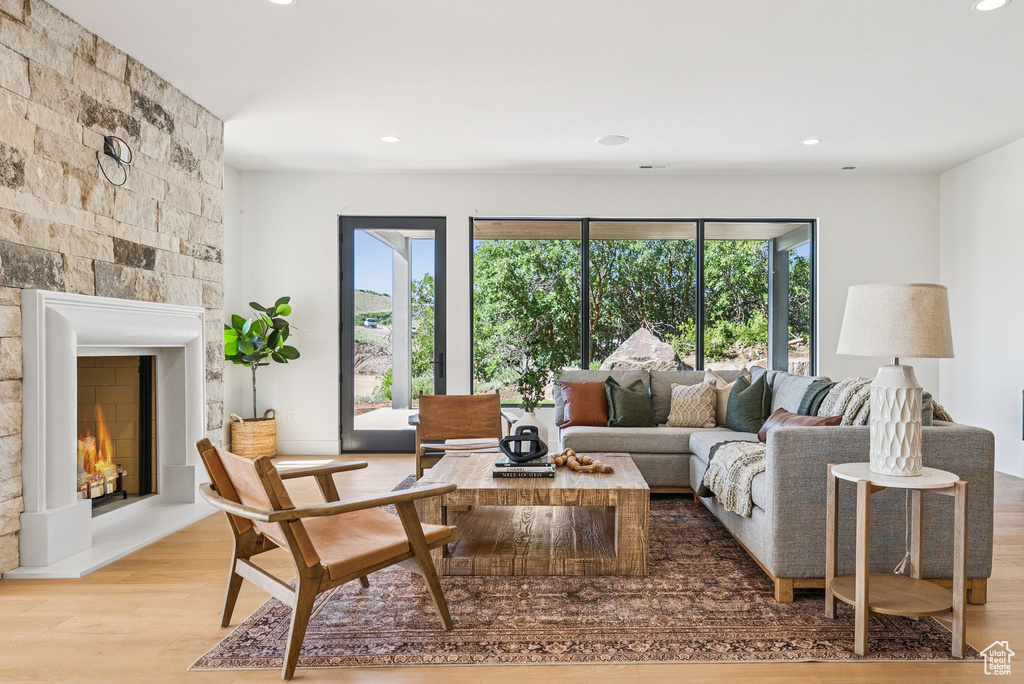Living area with a stone fireplace, wood finished floors, and recessed lighting