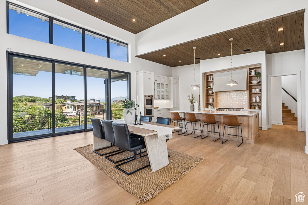 Dining area with wooden ceiling, a towering ceiling, recessed lighting, stairway, and light wood finished floors