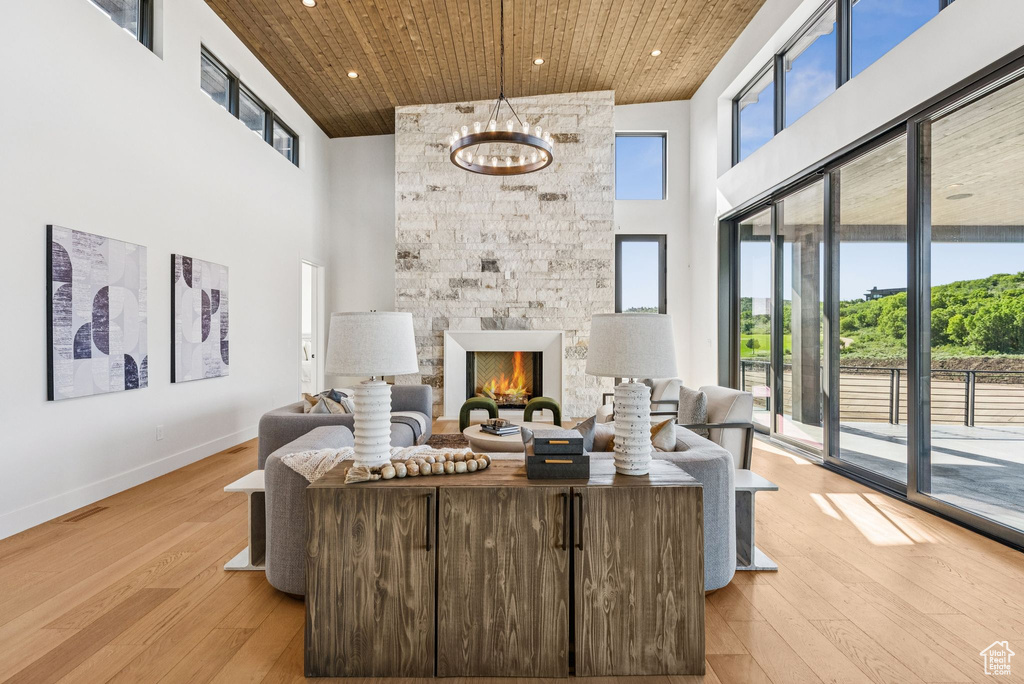 Living area featuring a towering ceiling, wooden ceiling, recessed lighting, light wood finished floors, and a fireplace