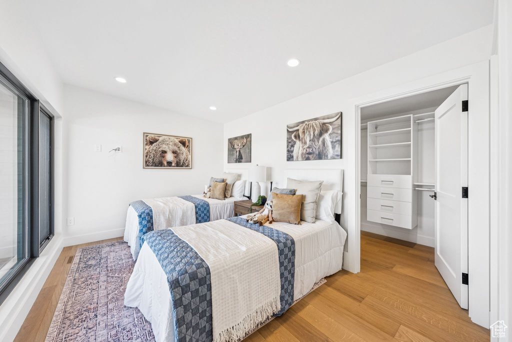 Bedroom with light wood-type flooring, a walk in closet, and recessed lighting